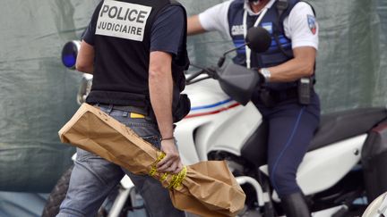 Un policier emporte l'arme avec laquelle un jeune homme a tu&eacute; trois personnes &agrave; Istres (Bouches-du-Rh&ocirc;ne), le 25 avril 2013. (GERARD JULIEN / AFP)