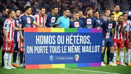 Les joueurs du PSG et de l'AC Ajaccio posent derrière une pancarte à l'occasion d'une journée de lutte contre l'homophobie, avant un match de Ligue 1, le 13 mai 2023 à Paris. (FRANCK FIFE / AFP)