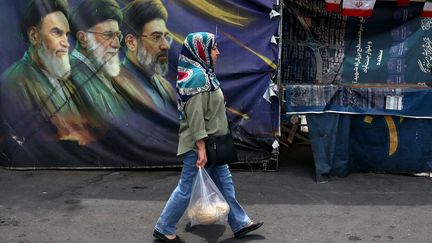 Une femme passe devant une affiche représentant les trois derniers guides suprêmes iraniens, le 29 mai à Téhéran (Iran).